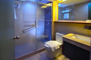 A modern bathroom with a glass-enclosed shower, a toilet, and a sink with a mirror above. - Sola Hotel (Laoag)