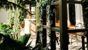 Un espacio al aire libre cubierto con una estructura de pérgola de madera adornada con plantas trepadoras.