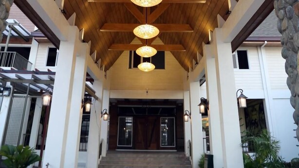 Una entrada cubierta con vigas de madera y pilares de piedra, que conduce a la entrada de un edificio.