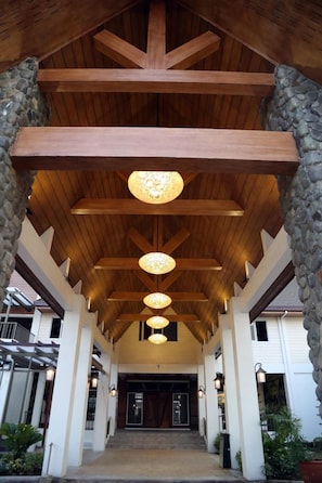 A covered entrance with wooden beams and stone pillars, leading to a building entrance. - Sola Hotel (Laoag)