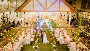 Una ceremonia de boda con invitados sentados a ambos lados del pasillo, decorado con arreglos florales y luces de cuerda.