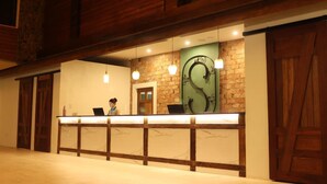 Un mostrador de recepción con una persona detrás, una pared decorativa verde y paneles de madera.