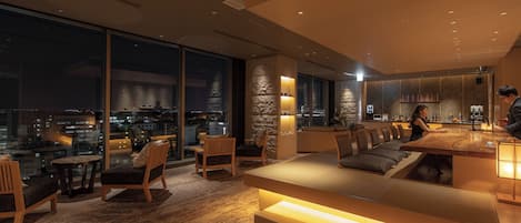 A modern interior with a seating area, large windows, and a city view.