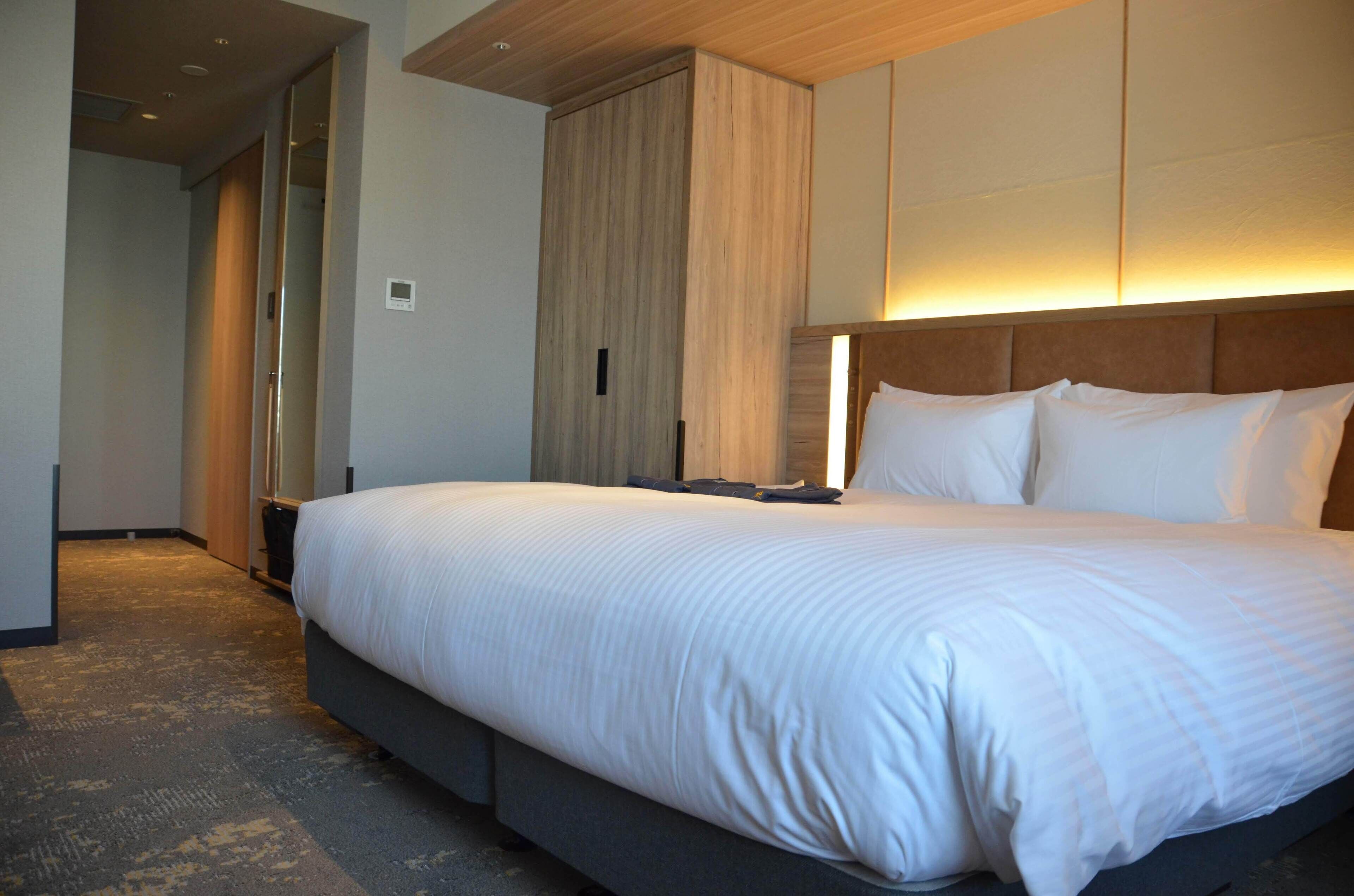 Una habitación de hotel con una cama grande, un armario y un espejo.