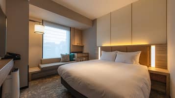 Ett modernt hotellrum med en stor säng, en sittgrupp med utsikt, ett skrivbord och en papperskorg.
