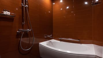 A modern bathroom with a freestanding bathtub, a showerhead, and a shelf with toiletries.