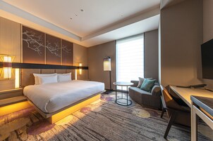 Una habitación de hotel moderna con una cama grande, un escritorio, un sofá y un televisor.