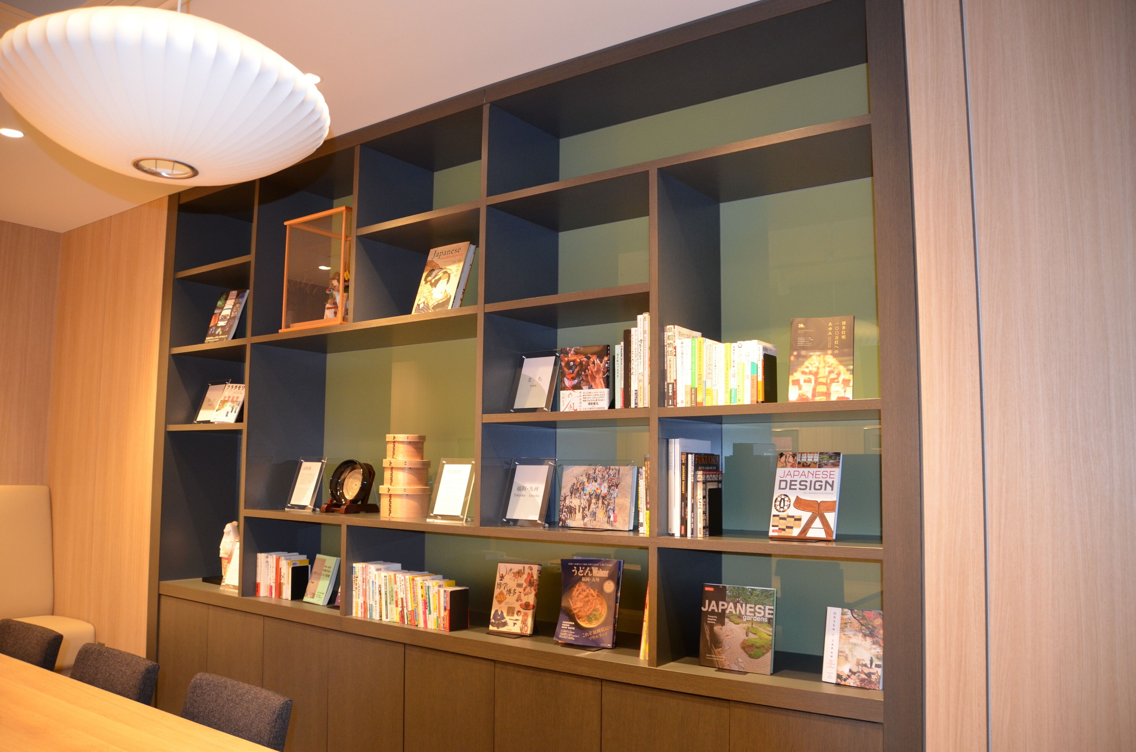 A library with bookshelves, a reading area, and a ceiling light fixture.