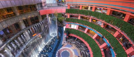 A multi-level atrium with a central water feature, multiple balconies, and a variety of seating areas.