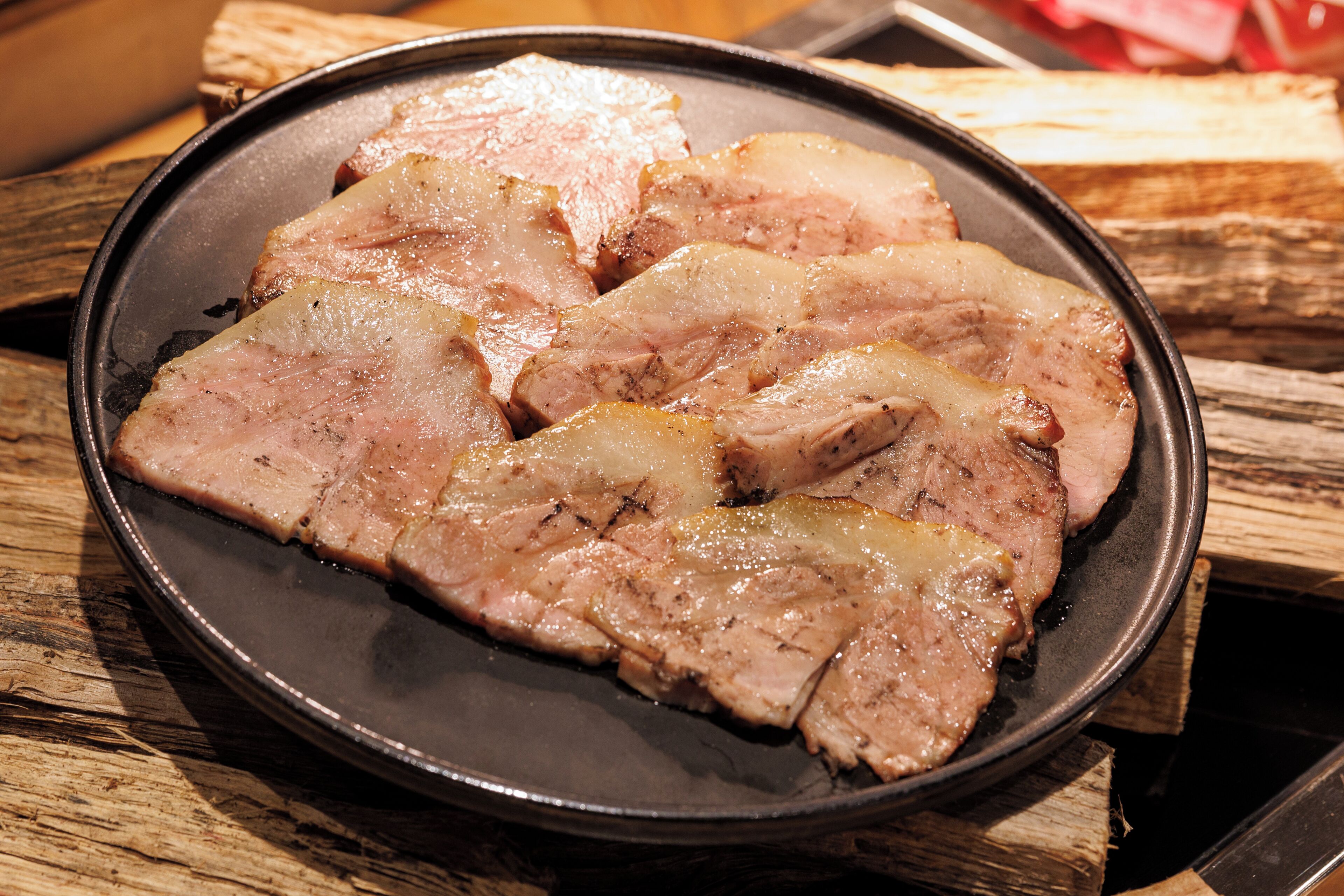 A plate of sliced meat on a wooden table.