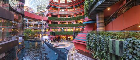 Un atrio de varios niveles con una fuente central, rodeado de vegetación y arquitectura moderna.