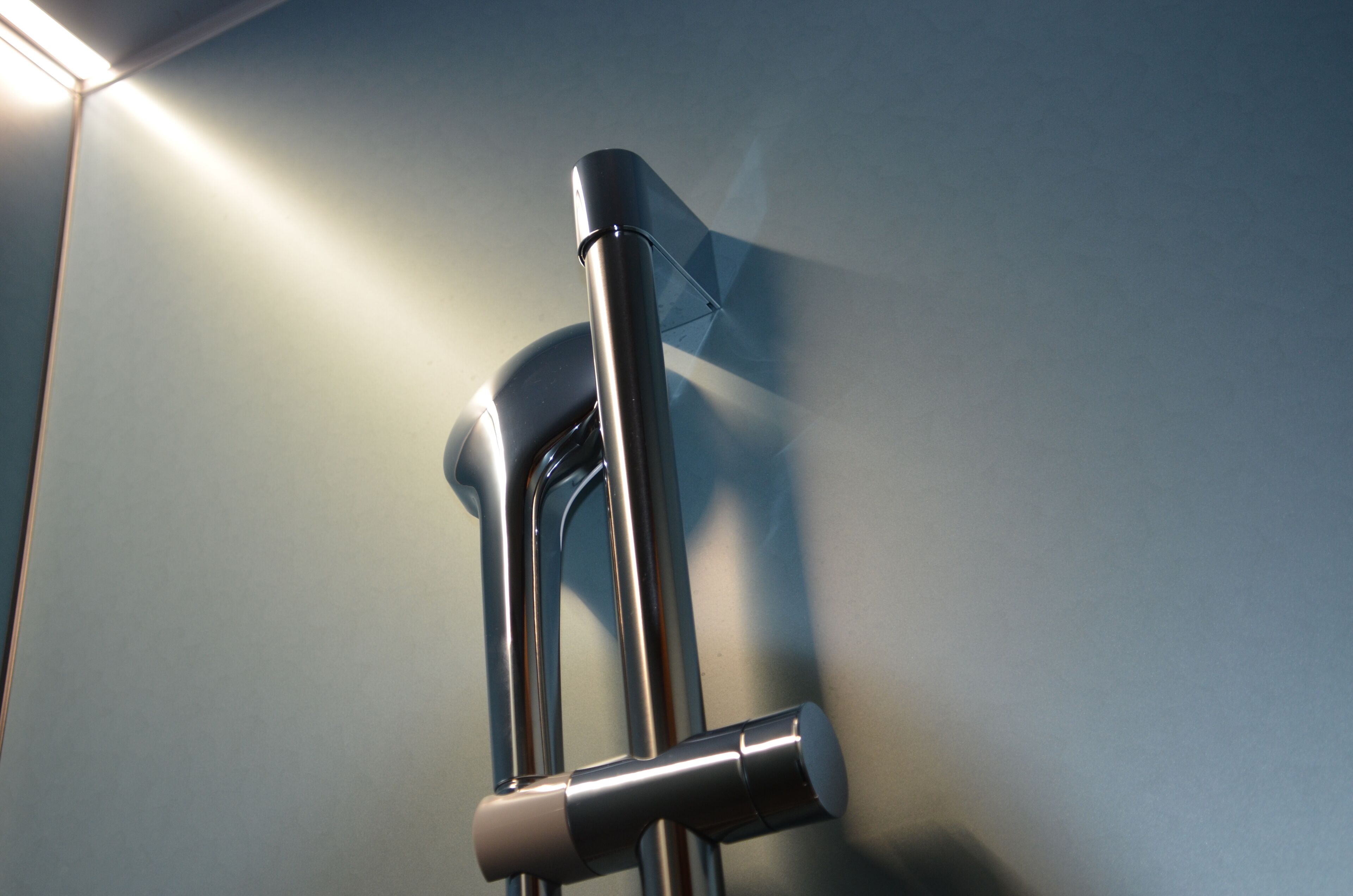 A metallic faucet mounted on a wall.