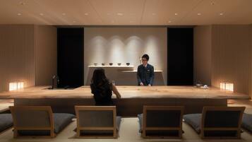 A modern hotel lobby with a reception desk, seating area, and decorative elements.