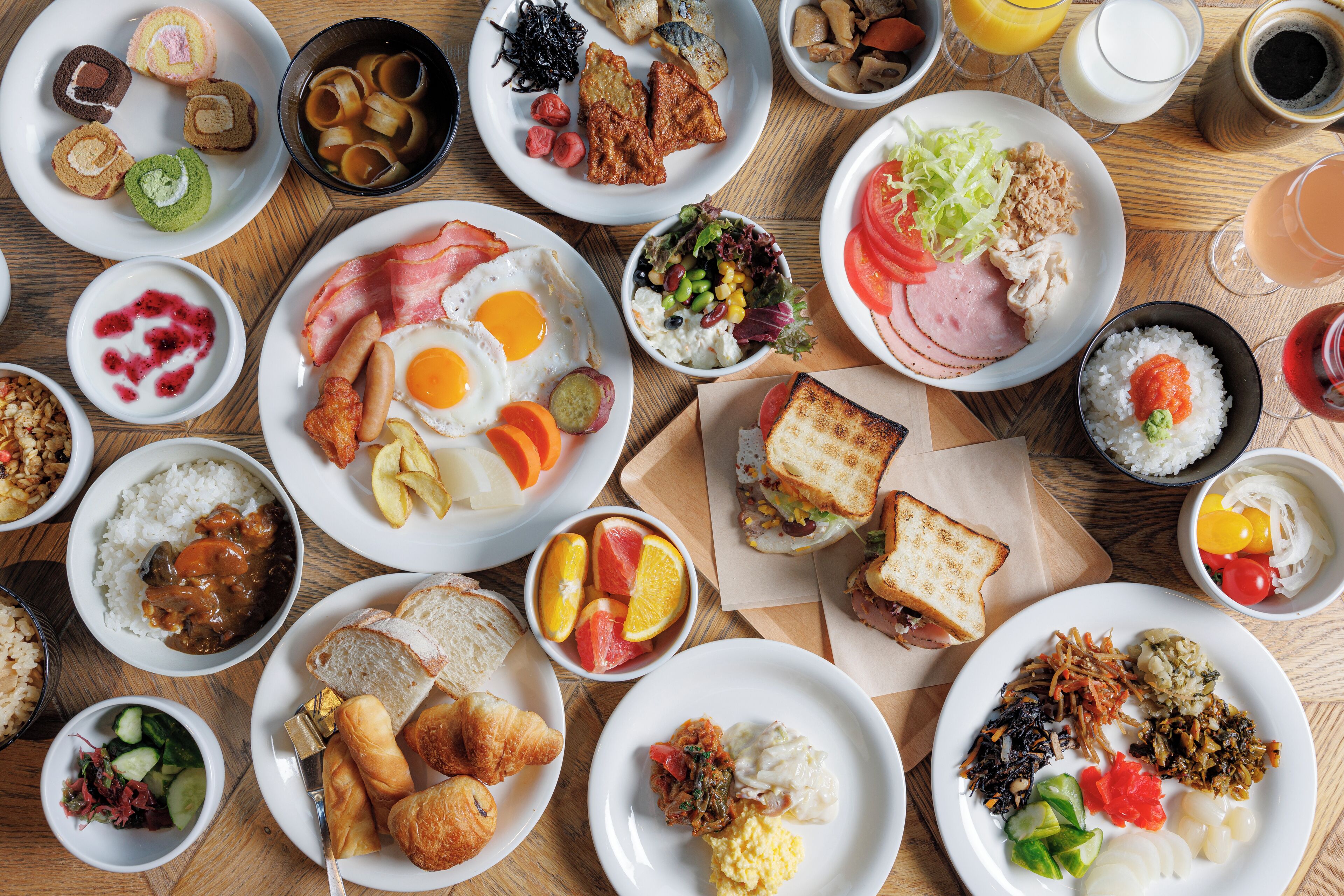 A variety of breakfast dishes including eggs, toast, and fruit on a wooden table.