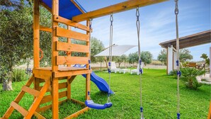A wooden play structure with a slide and swings in a grassy backyard. - Awesome home in Menfi AG with WiFi (Menfi AG)