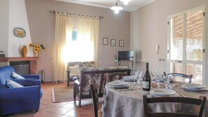 A living room with a sofa, a dining table set for a meal, a fireplace, and a television. - Awesome home in Menfi AG with WiFi (Menfi AG)