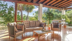 An outdoor patio with wicker furniture, a wooden table, and potted plants. - Awesome home in Menfi AG with WiFi (Menfi AG)