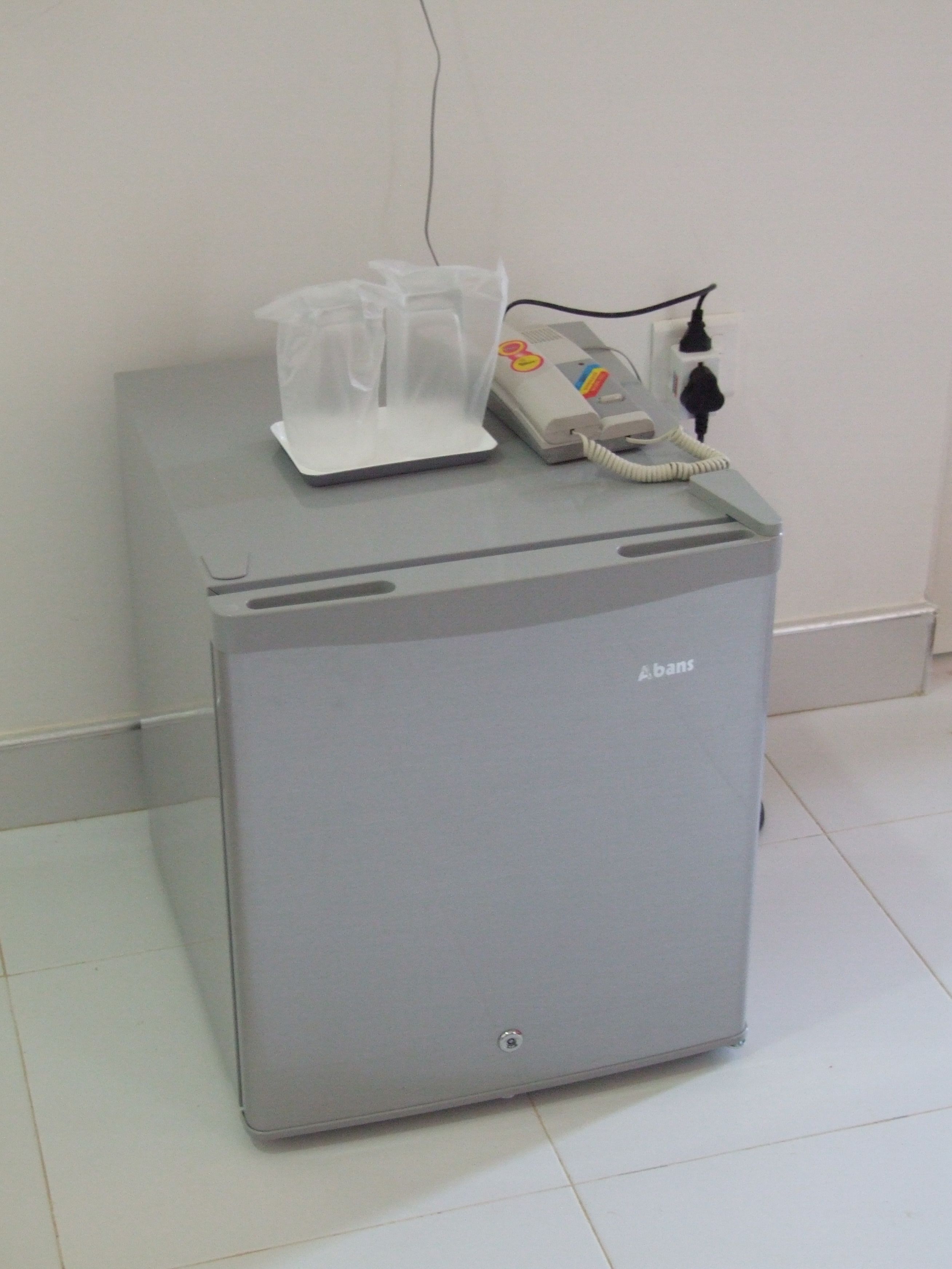 A medical device with a phone and a plastic container on top, placed on a grey cabinet.