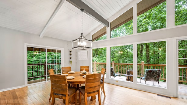 Un vaste espace dédié à la salle à manger, avec une table et des chaises en bois, et de grandes fenêtres donnant sur un jardin luxuriant.