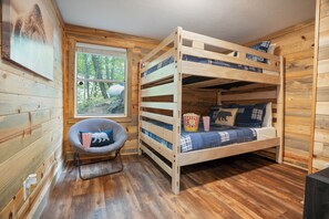 A bunk bed with a window, a chair, and a popcorn container.