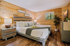 A wooden-paneled bedroom with a bed, bedside tables, a window, and a mirror.