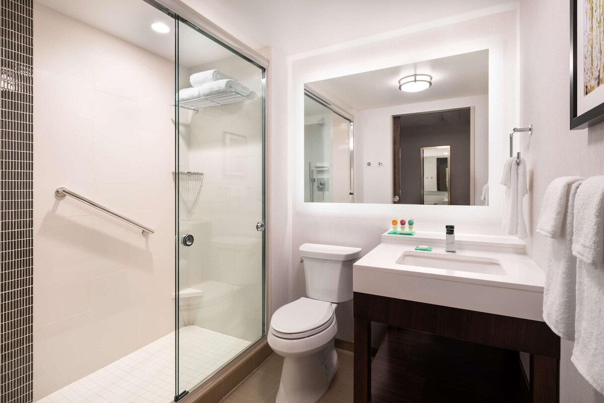 A modern bathroom with a glass shower enclosure, a white toilet, and a sink with a mirror above it.