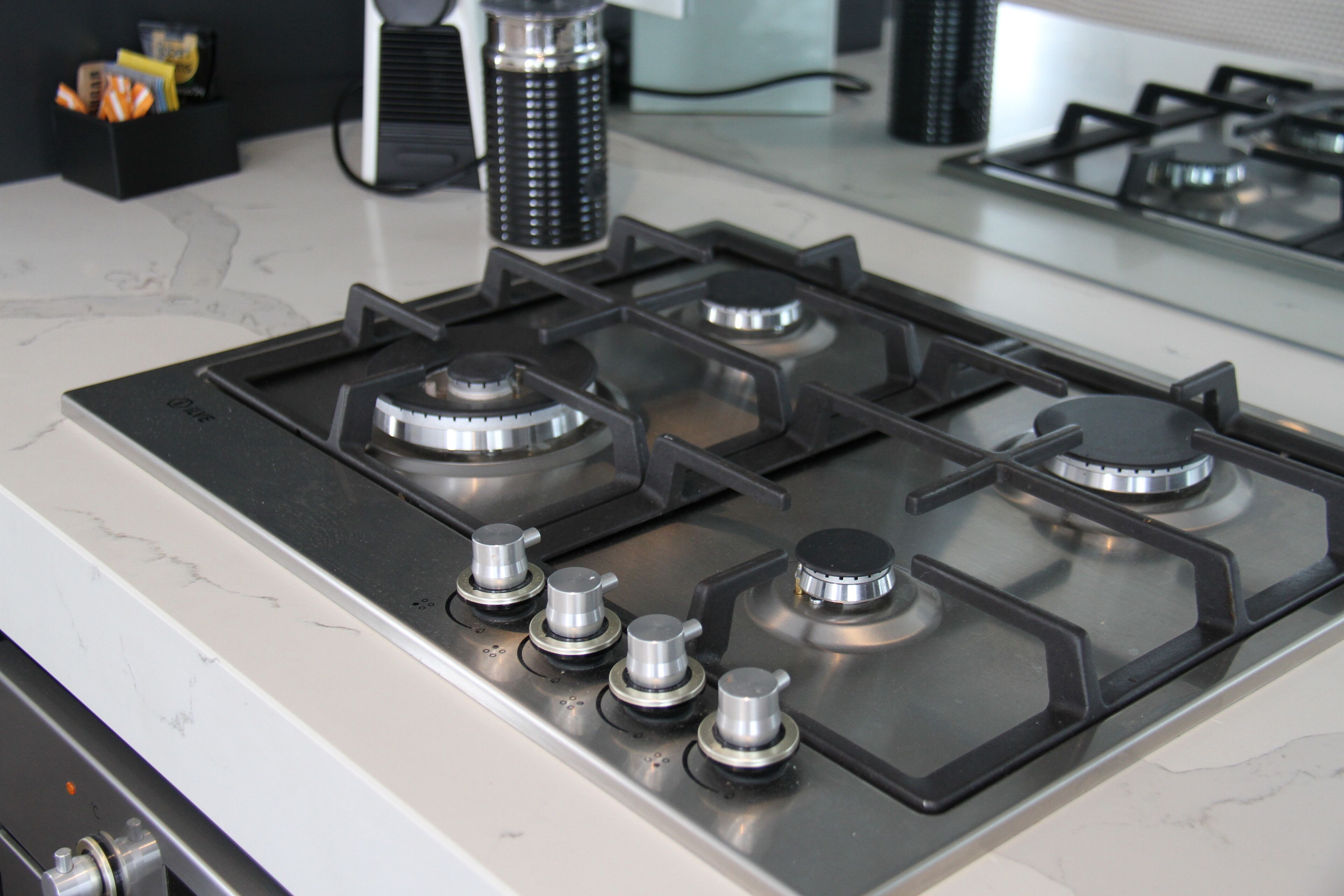 Una cucina con un piano cottura a gas, una moka e un contenitore con degli snack.