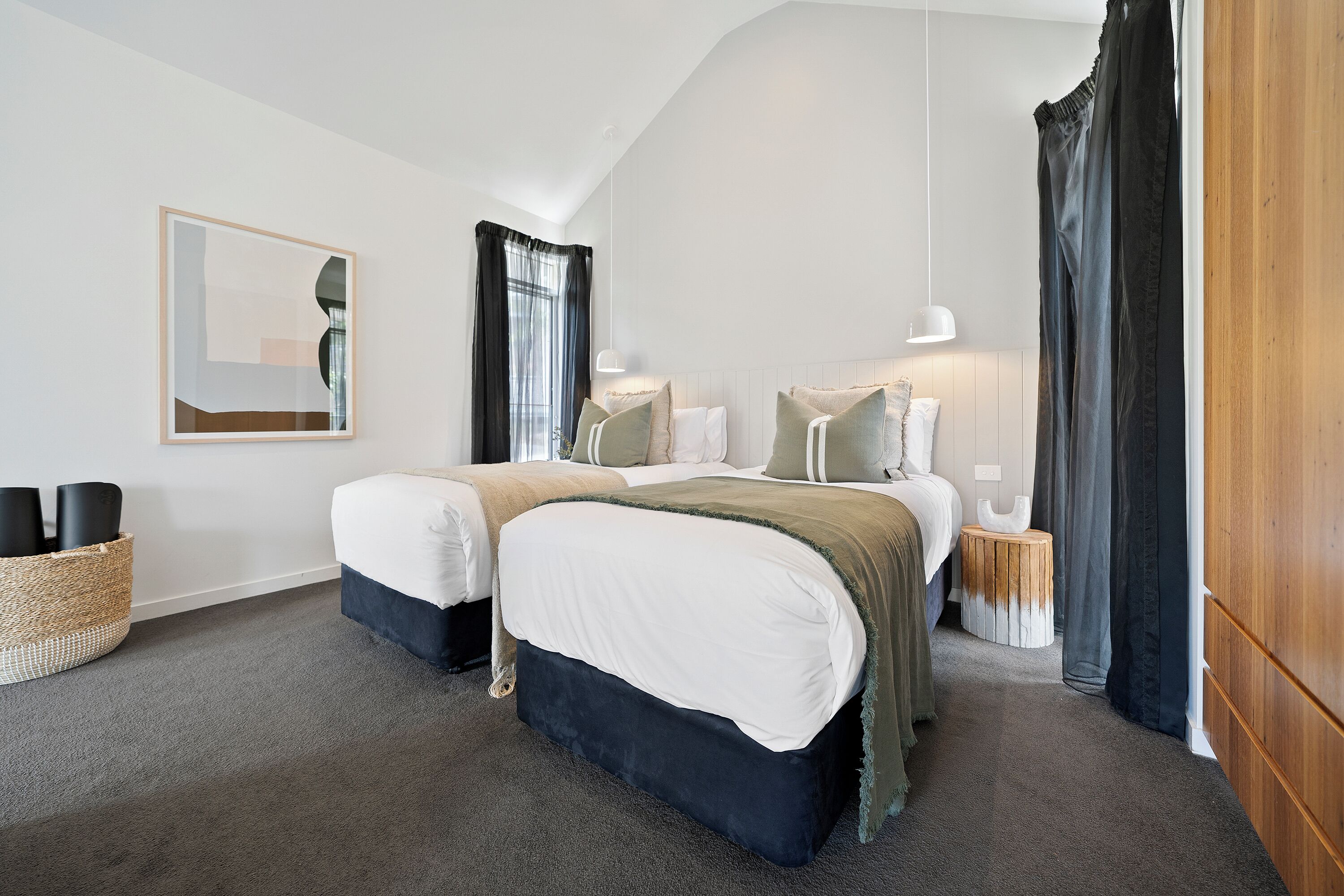 Een moderne slaapkamer met twee bedden, een grote spiegel en een houten garderobe.