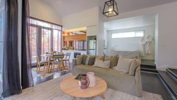 A modern living room with a sofa, coffee table, and dining area.