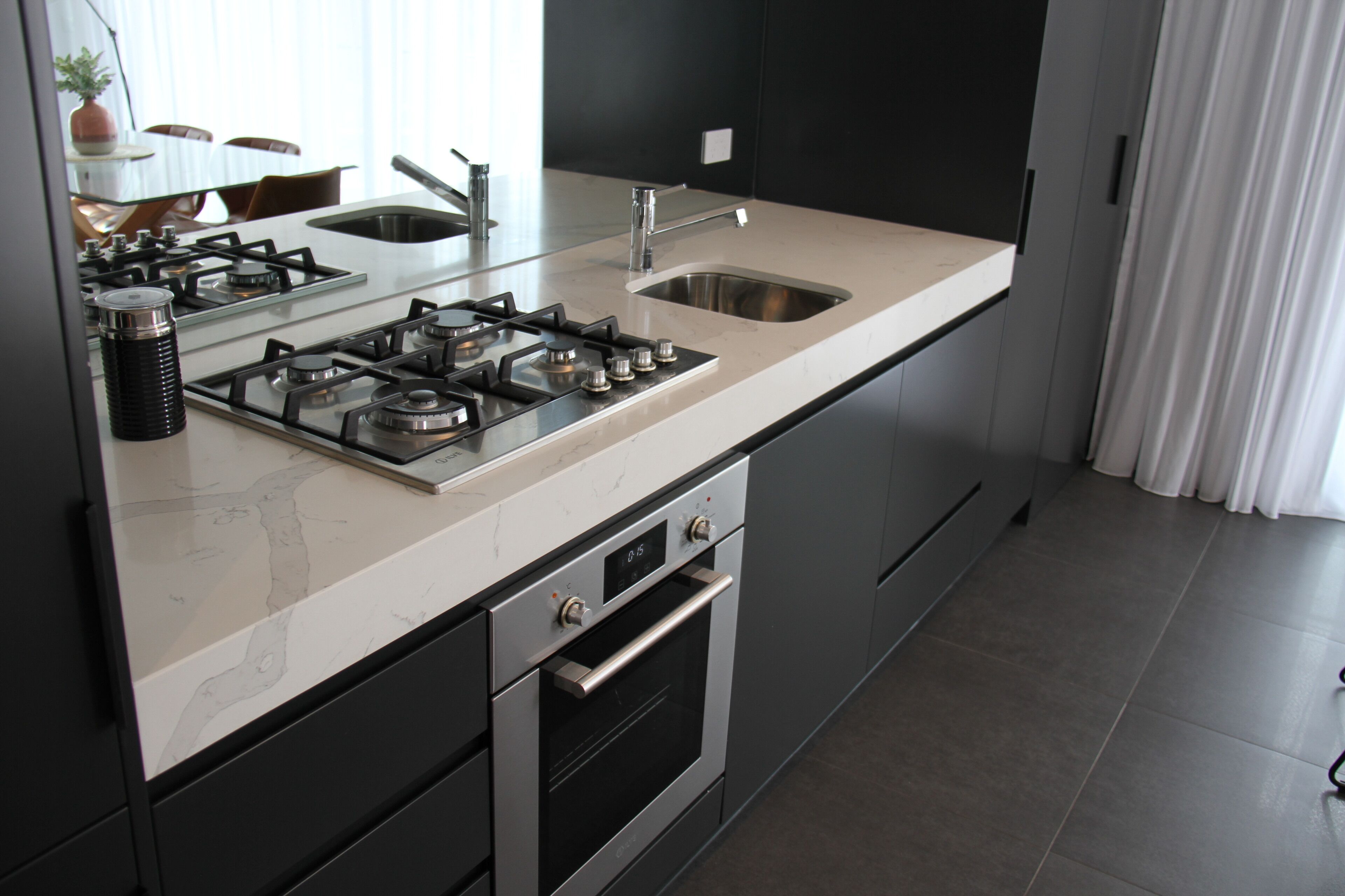 Eine moderne Küche mit Gasherd, Backofen, Spüle und Edelstahlgeräten.