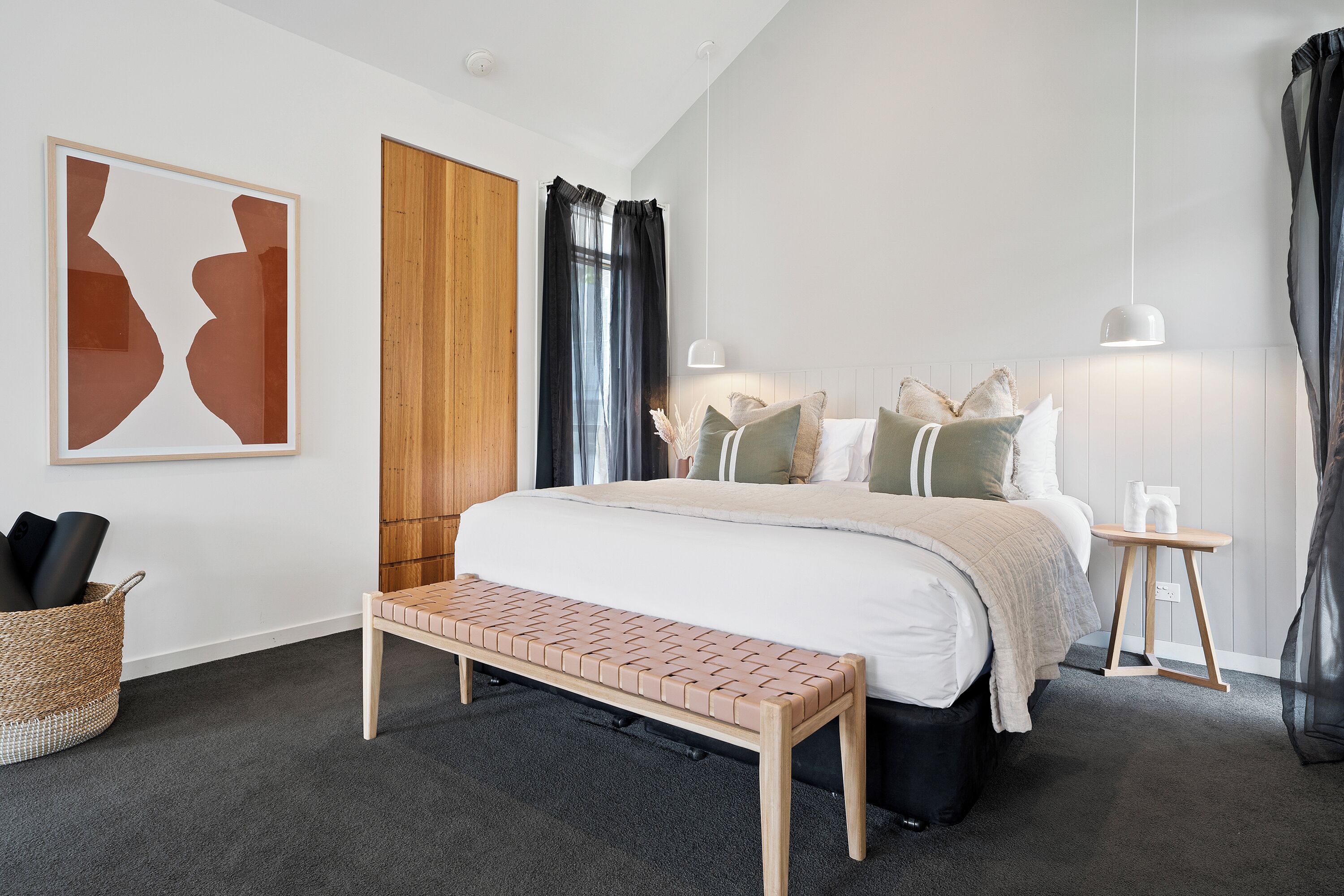 Ein modernes Schlafzimmer mit einem großen Bett, einer Bank, einem Nachttisch und einer Wandlampe.