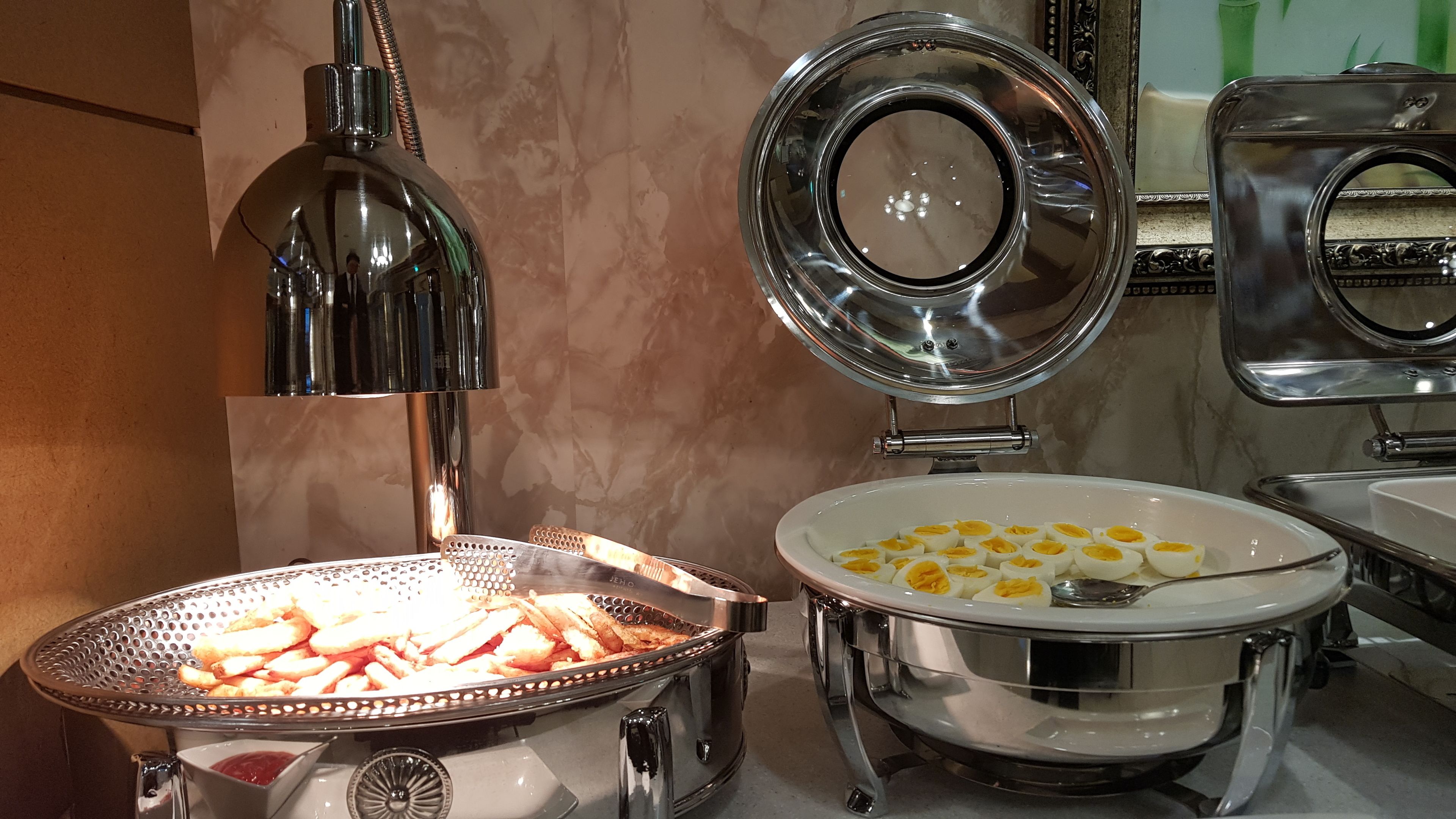 Een buffetopstelling met diverse gerechten, waaronder een schaal met plakjes gekookte eieren en een schaal met gefrituurde snacks.
