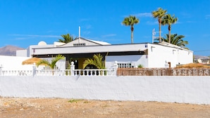 A white building with a flat roof, palm trees, and a white fence. - Hearth away from house BREIA (Tías)