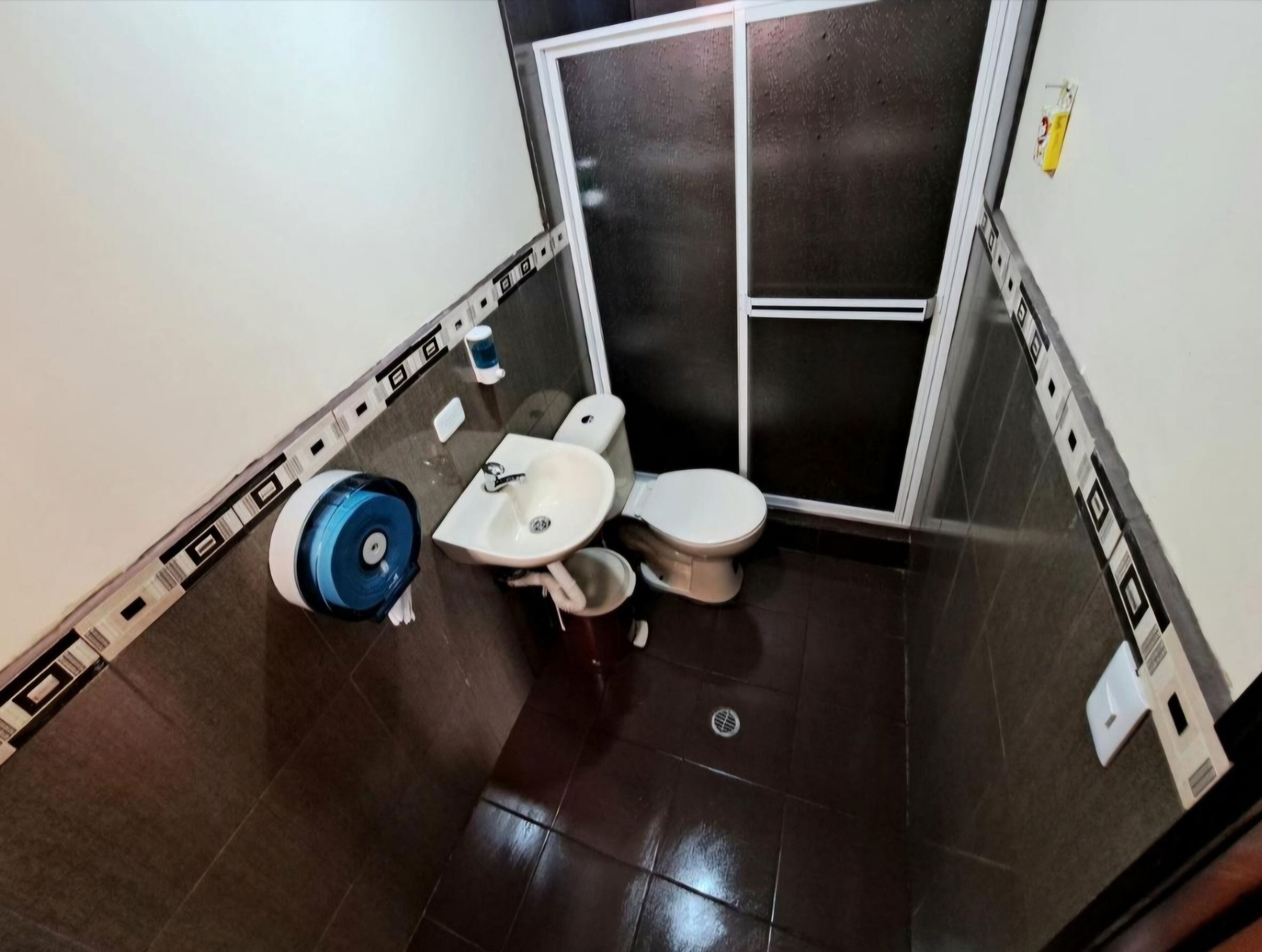 A small bathroom with a toilet, sink, and a blue cleaning machine.