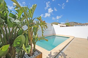 Une piscine avec un mur blanc et une montagne en arrière-plan.