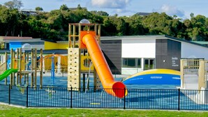 A playground with a slide, climbing structures, and a pool area.
