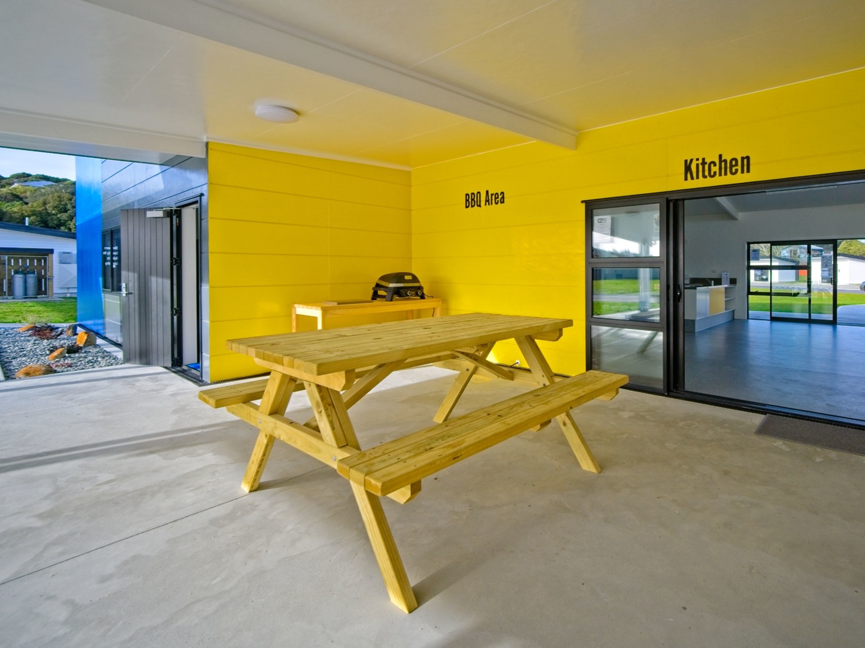 Una pared amarillo brillante con un cartel que dice 'Cocina' y 'Área de Barbacoa'.