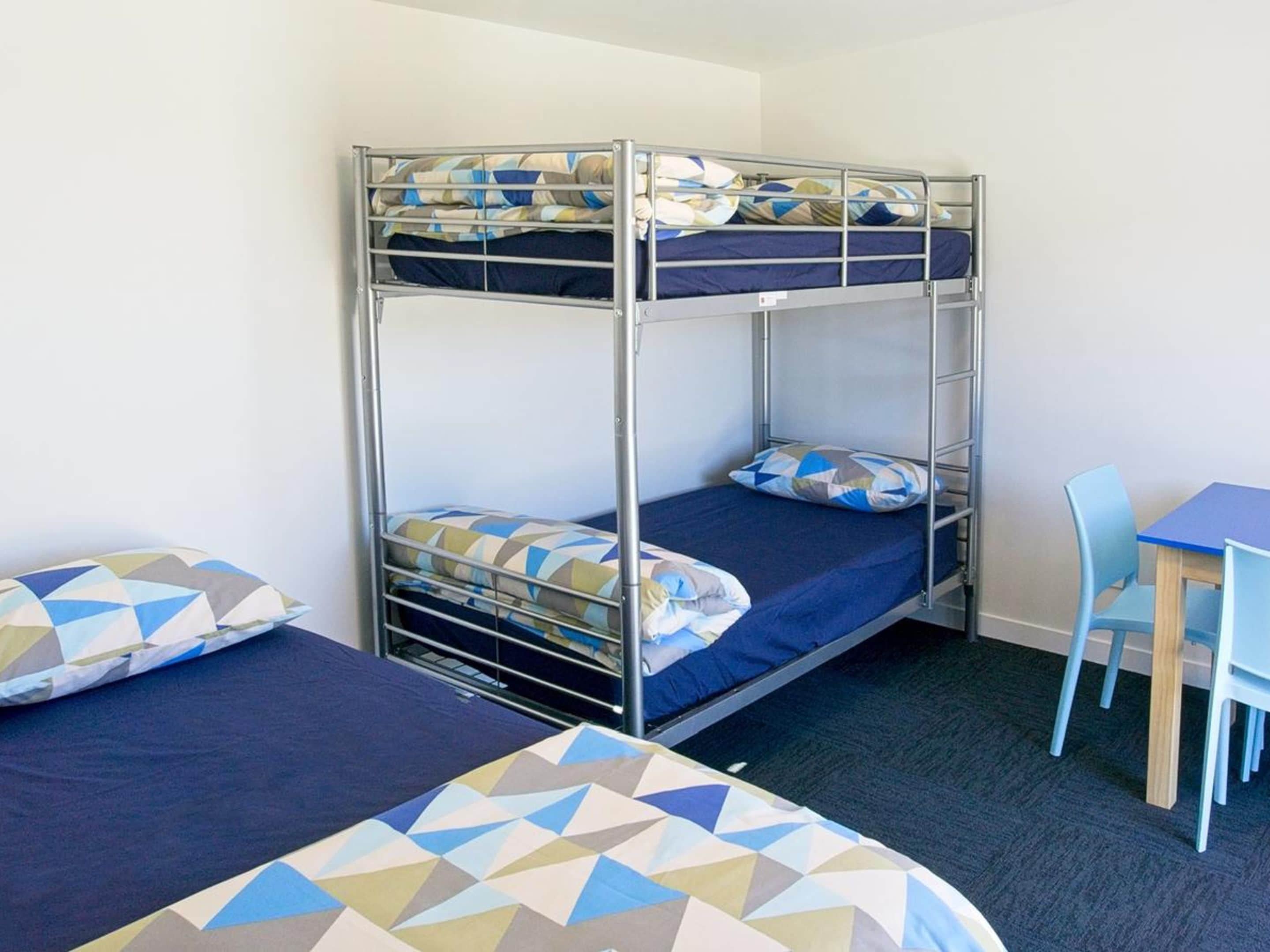 A bunk bed room with a desk and chair.