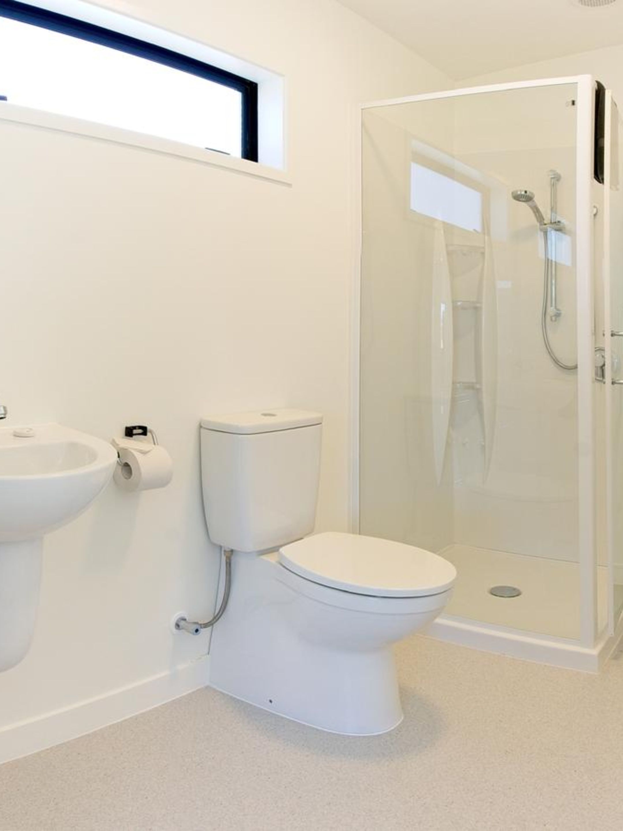 A modern bathroom with a toilet, sink, and glass-enclosed shower.