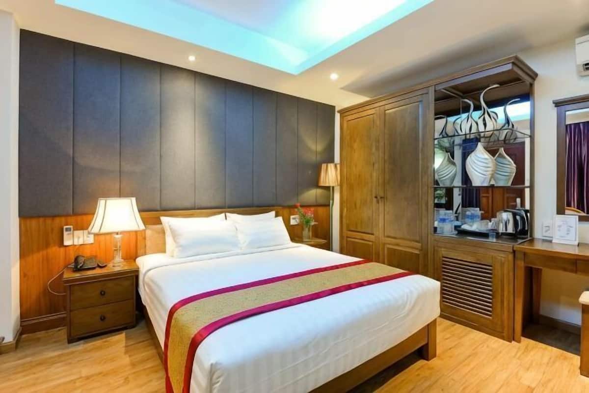 Ein Hotelzimmer mit Bett, Nachttisch, Lampe, Kleiderschrank und Blick zum Himmel.