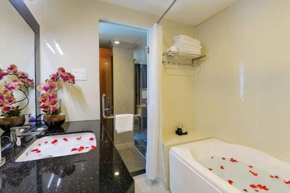 Ein Badezimmer mit Doppelwaschbecken, einer Badewanne mit Rosenblüten und einer Duschkabine.
