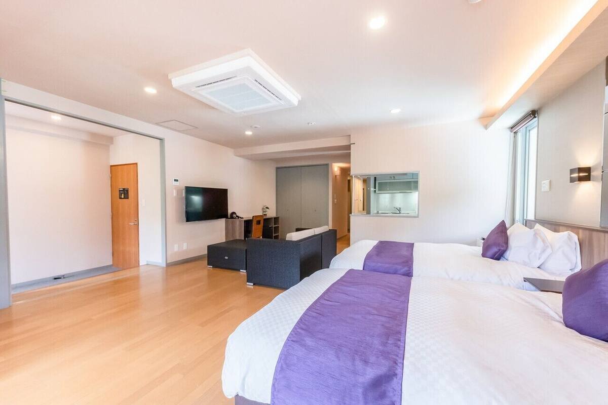 A modern hotel room with a large bed, a desk, a flat-screen TV, and a large window.