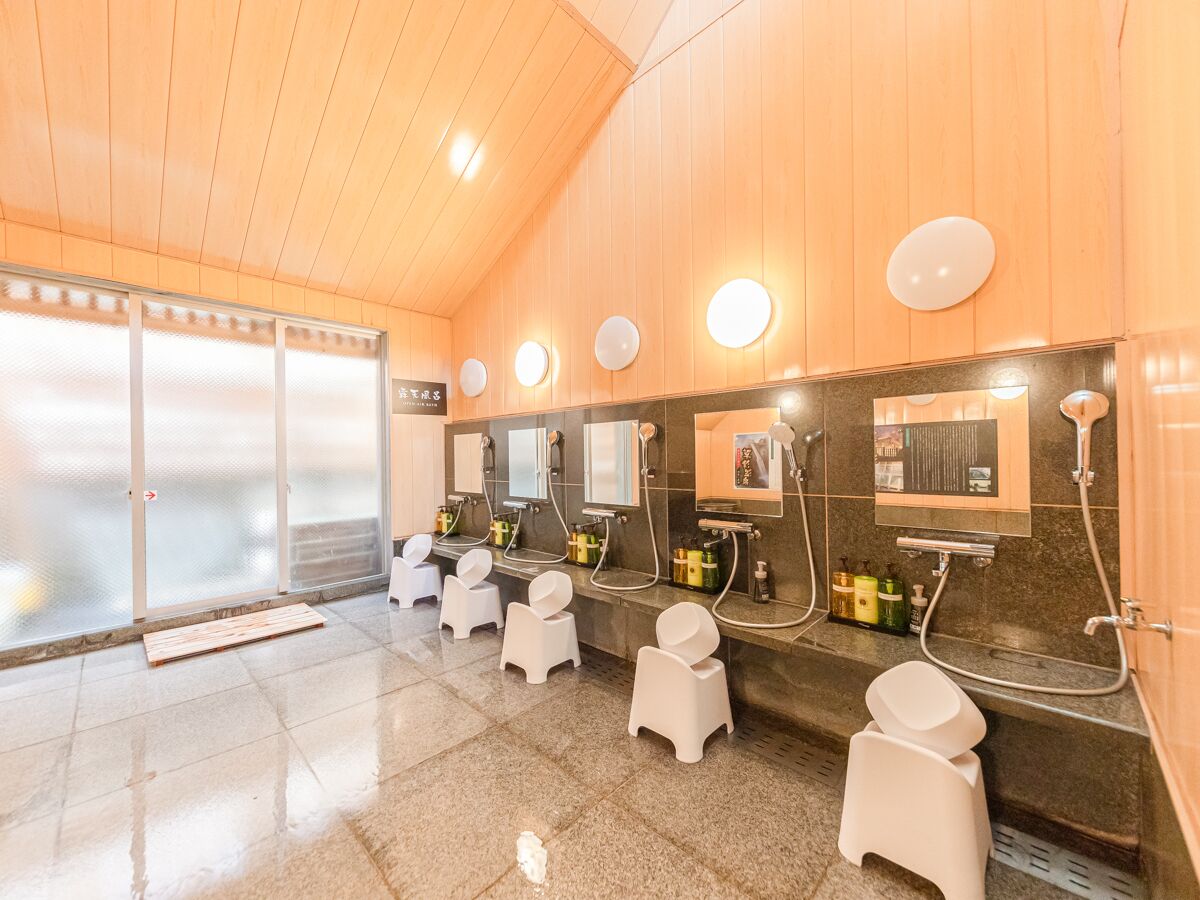 A modern bathroom with multiple sinks, mirrors, and individual toilet stalls.