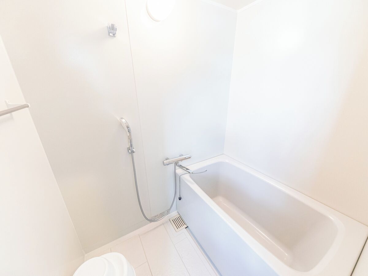 Un baño blanco con bañera, ducha y retrete.