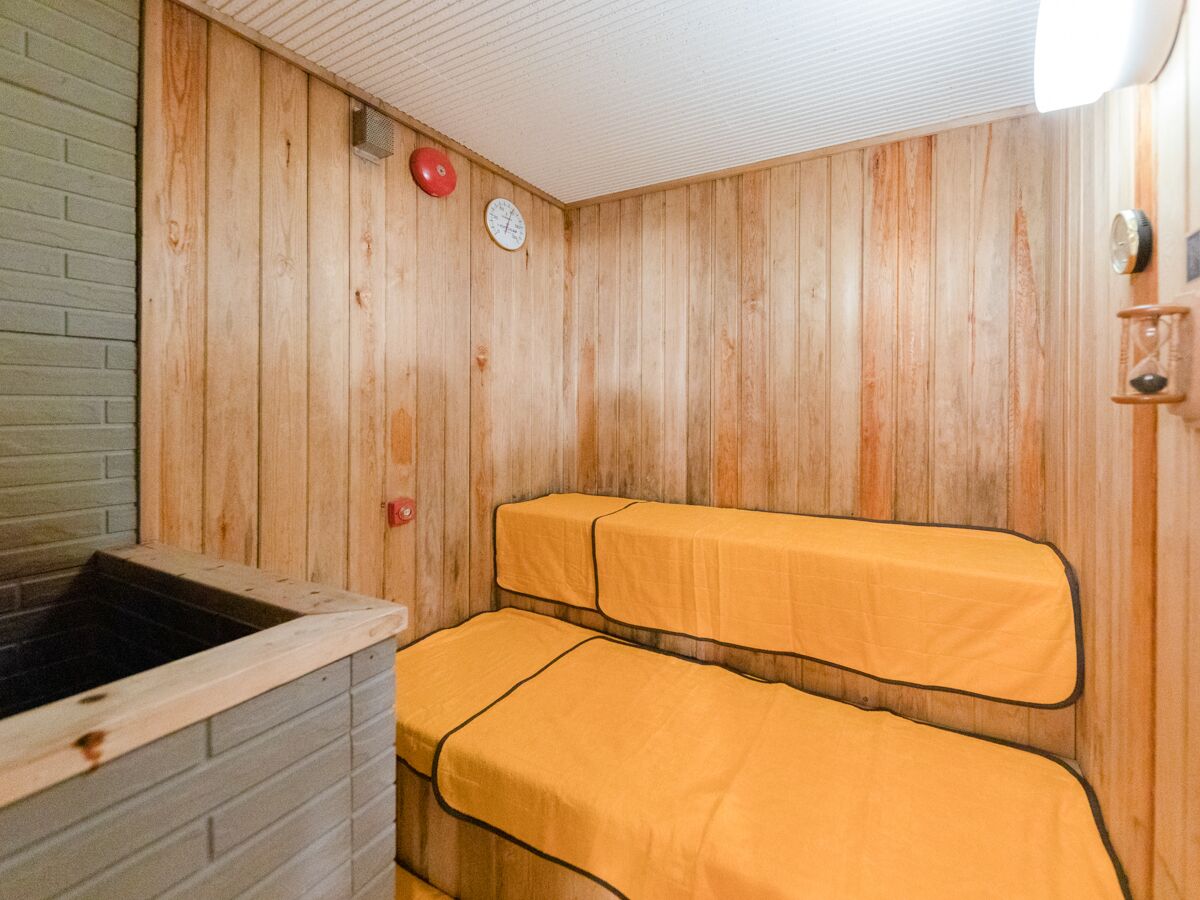 A sauna room with wooden walls, a bench, and a hot tub.