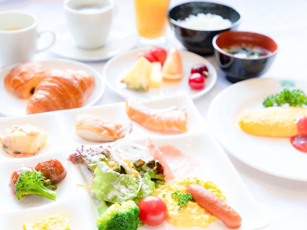 A breakfast spread with various dishes including croissants, fruit, and a salad.