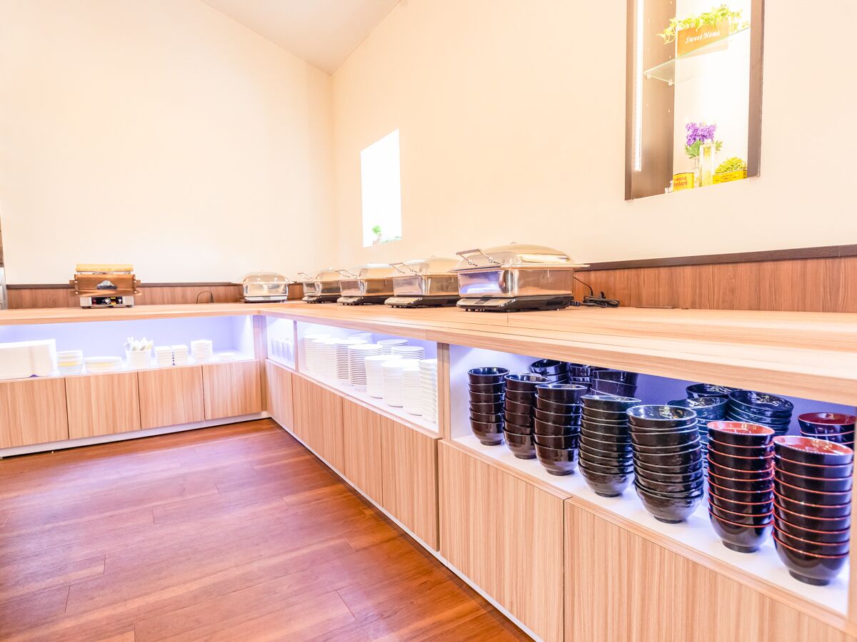A modern kitchen with wooden cabinets, a long counter, and stacks of black and red bowls.