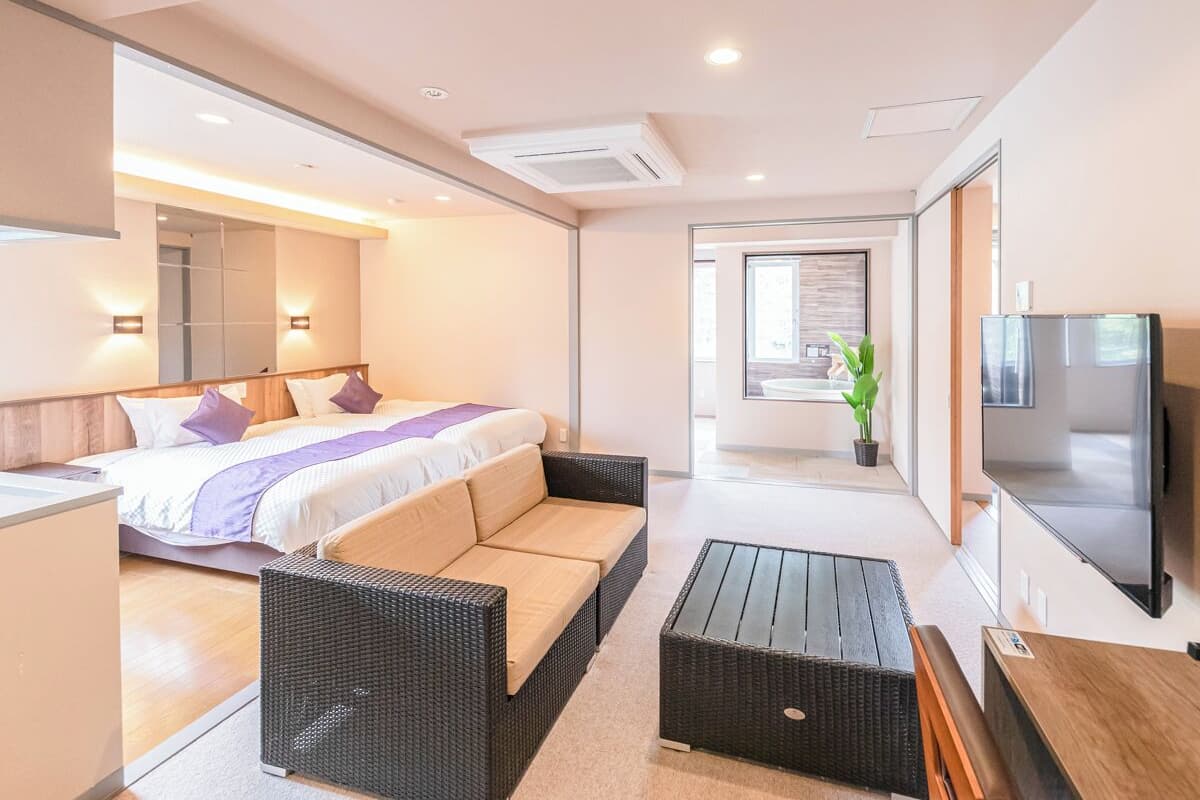 A modern hotel room with a bed, sofa, and TV.