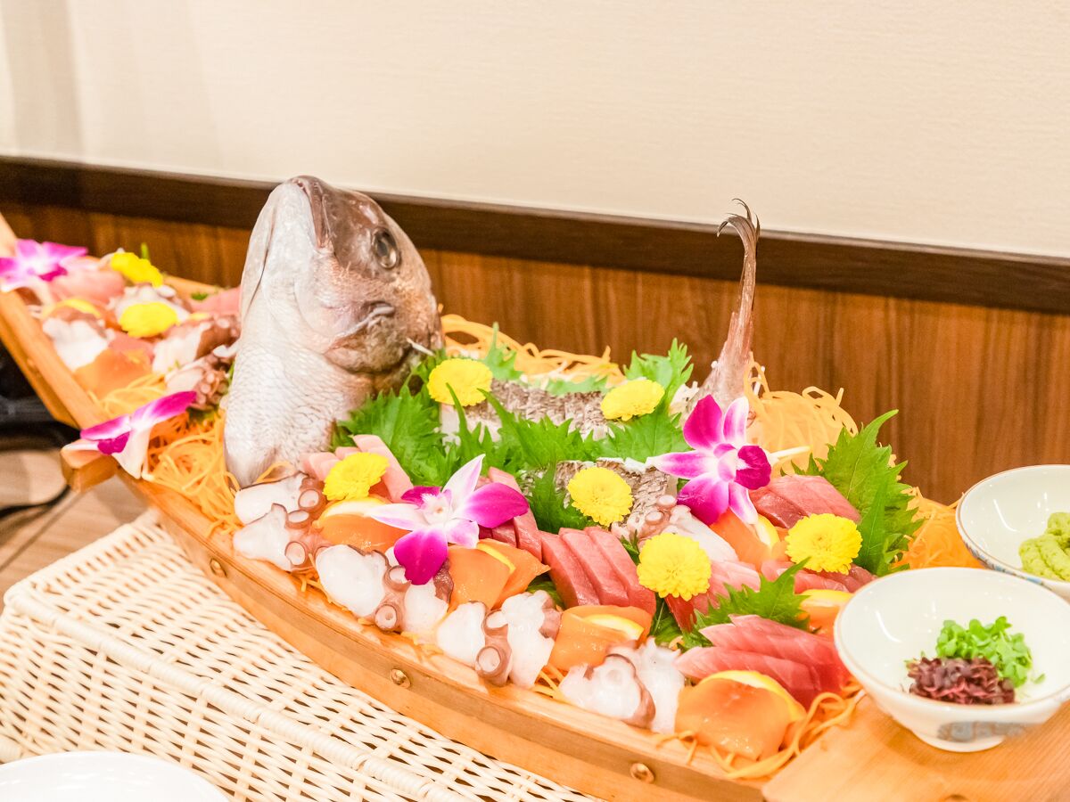 Un plato de sushi con diferentes tipos de pescado y guarniciones sobre una bandeja de madera.