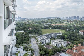 A high-rise building with multiple floors, a view of a cityscape with various buildings, and a green park area. - Regalia Residence by Cobnb (Kuala Lumpur)
